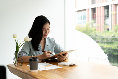 Young woman using laptop while sitting on table