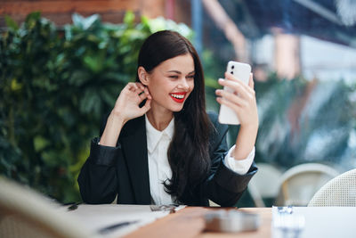 Young woman using mobile phone while sitting in cafe