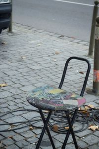 Close-up of empty chairs on sidewalk by street in city