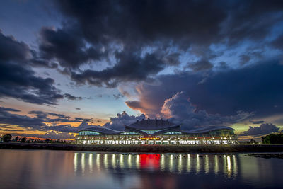 Illuminated bridge over water against sky at sunset