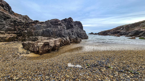 Rock formations on beach against sky