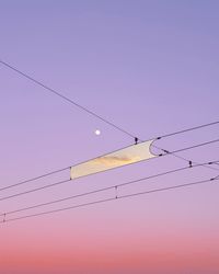 Low angle view of birds perching on cable against sky