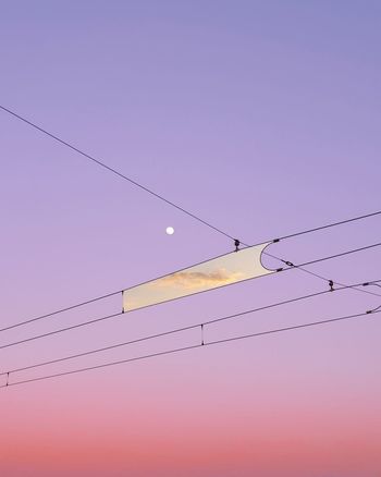 Digital composite image of clouds amidst cables against sky during sunset