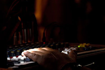 Cropped hand of dj using sound mixer in darkroom