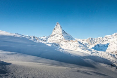 Scenic view of snowcapped mountains against clear blue sky