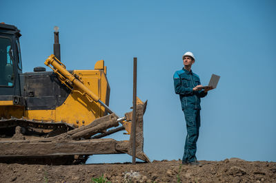 Rear view of man standing on field against clear sky