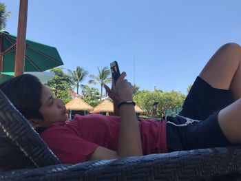 Rear view of woman sitting on seat against sky