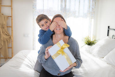 Little child closes the mothers eyes to give her a gift