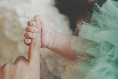 Close-up of mother and daughter with holding hands at home