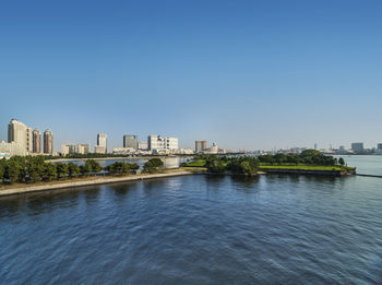 View of the bay of odaiba with daiba park and the beach in the distance.