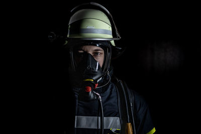 Man wearing hat standing against black background