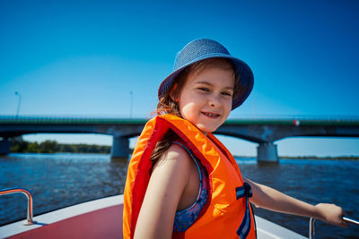 Portrait of smiling girl wearing life jacket standing in boat