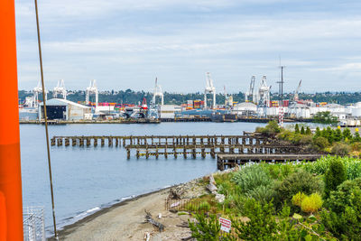 Sailboats on pier at harbor against sky