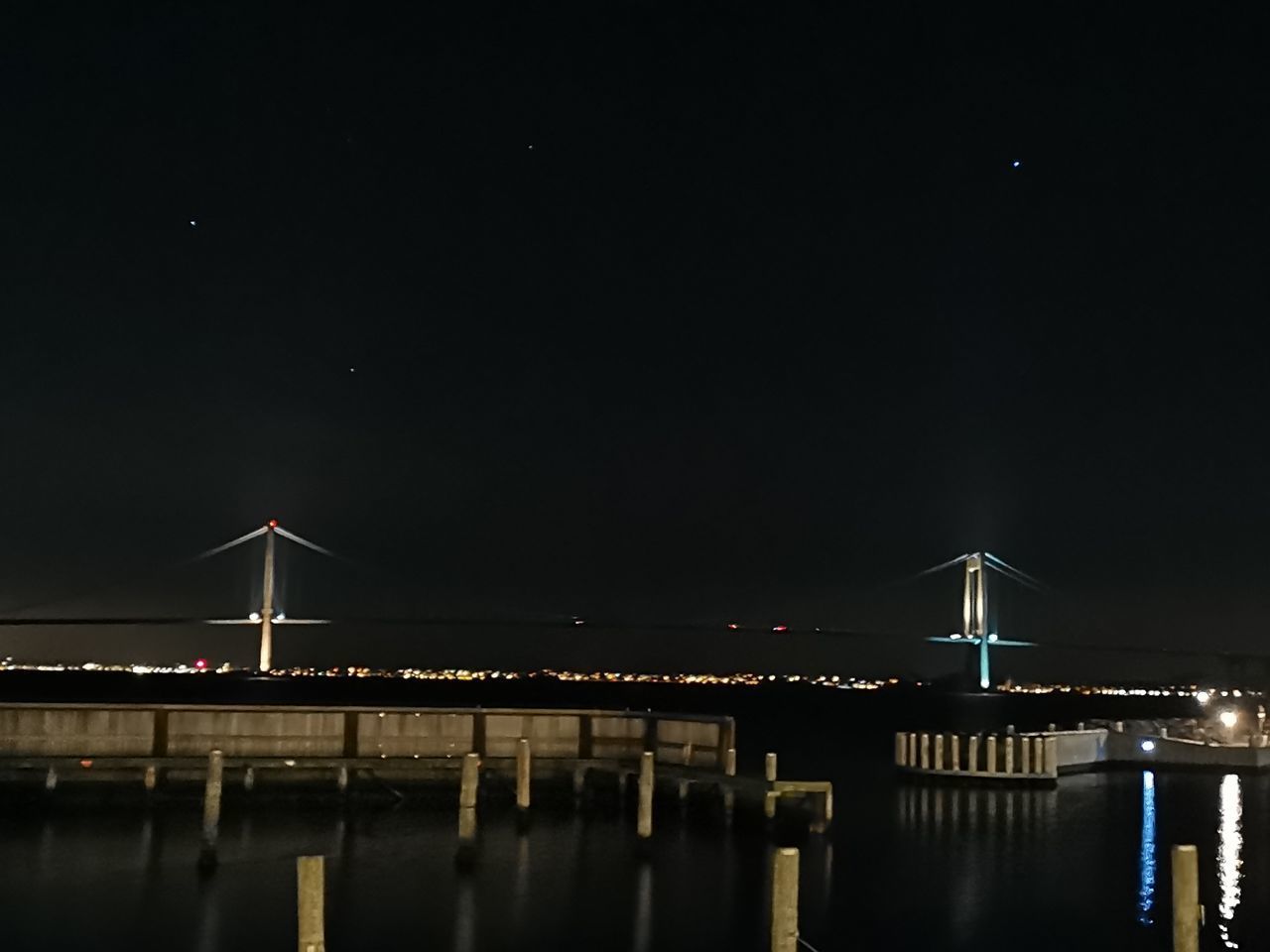 ILLUMINATED BRIDGE OVER RIVER AT NIGHT