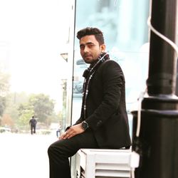 Portrait of young man sitting on bench outdoors