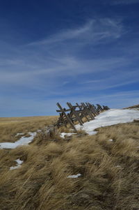 Fence by snow on grassy field during winter