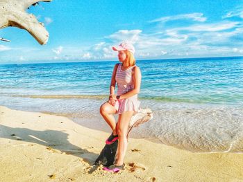 Full length of happy woman standing on beach against sky