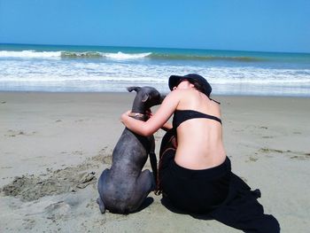 Woman with dog on beach against sky