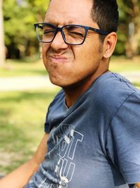 Young man wearing eyeglasses while making face in park