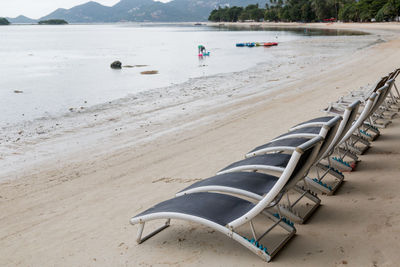 Deck chairs on beach against mountain
