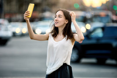 Young woman taking selfie on street