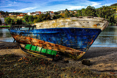 Old boat moored on beach against sky