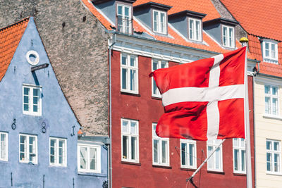 Old houses along the nyhavn canal or new harbour, entertainment district in copenhagen, danish flag