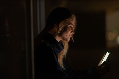 Side view of young woman using mobile phone