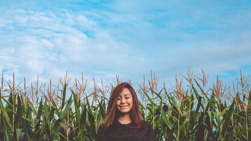 Smiling woman standing against plants