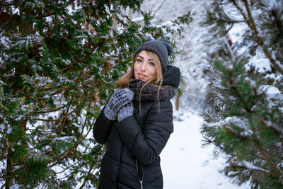 Portrait of young woman standing against plants