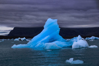 Scenic view of icebergs in sea against sky during winter