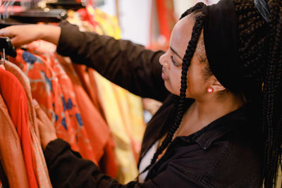 Side view of young woman looking at clothes in fashion store