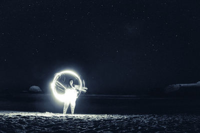Girl playing in the night making circles of light with the stars shining behind