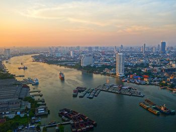 High angle view of cityscape by river against sky during sunset