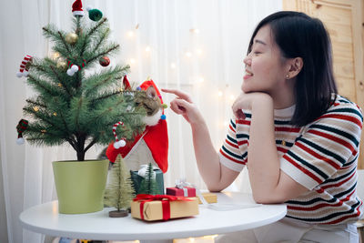 Portrait of young woman holding christmas tree at home