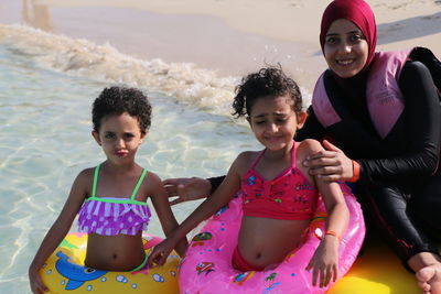 Portrait of happy mother with daughters enjoying at beach