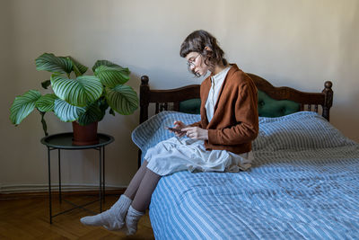 Portrait of young woman sitting on bed at home