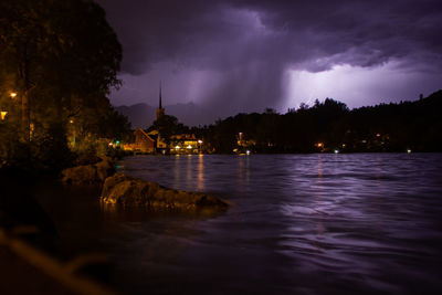 Panoramic view of illuminated buildings by river against sky