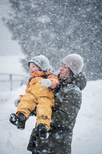 Mother playing with son while standing on snow