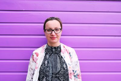 Portrait of woman standing against purple wall
