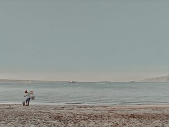 Man standing on shore at beach against sky