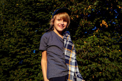 Portrait of young woman standing against trees