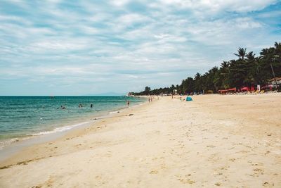 Group of people on beach against sky 