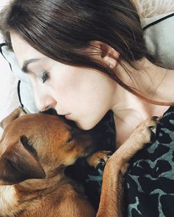 Close-up of woman with dog on bed at home