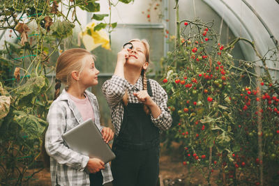 Young woman holding flower standing by plants