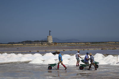 Salt people by sea against clear sky