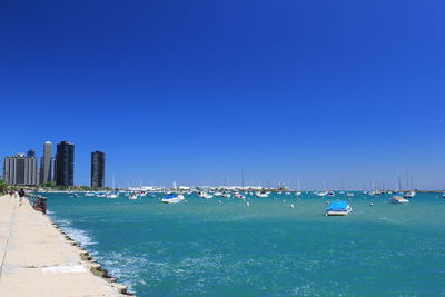 Sailboats in sea against clear blue sky