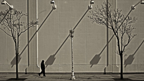 Silhouette man walking footpath by building