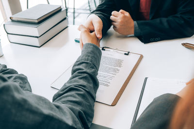 Midsection of man reading book on table