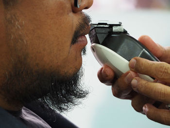 Cropped hands of man shaving customer mustache in hair salon